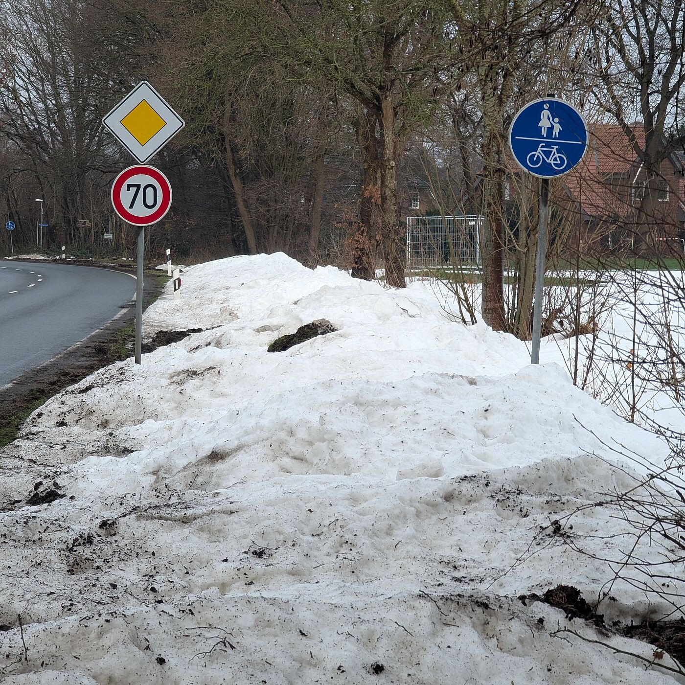Ein Radweg, voll mit Schnee, danenben eine freie Fahrbahn